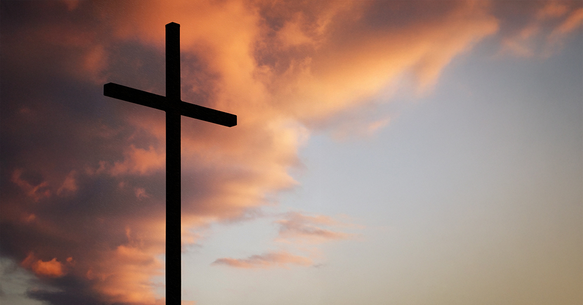 A cross set against a sunset sky with clouds
